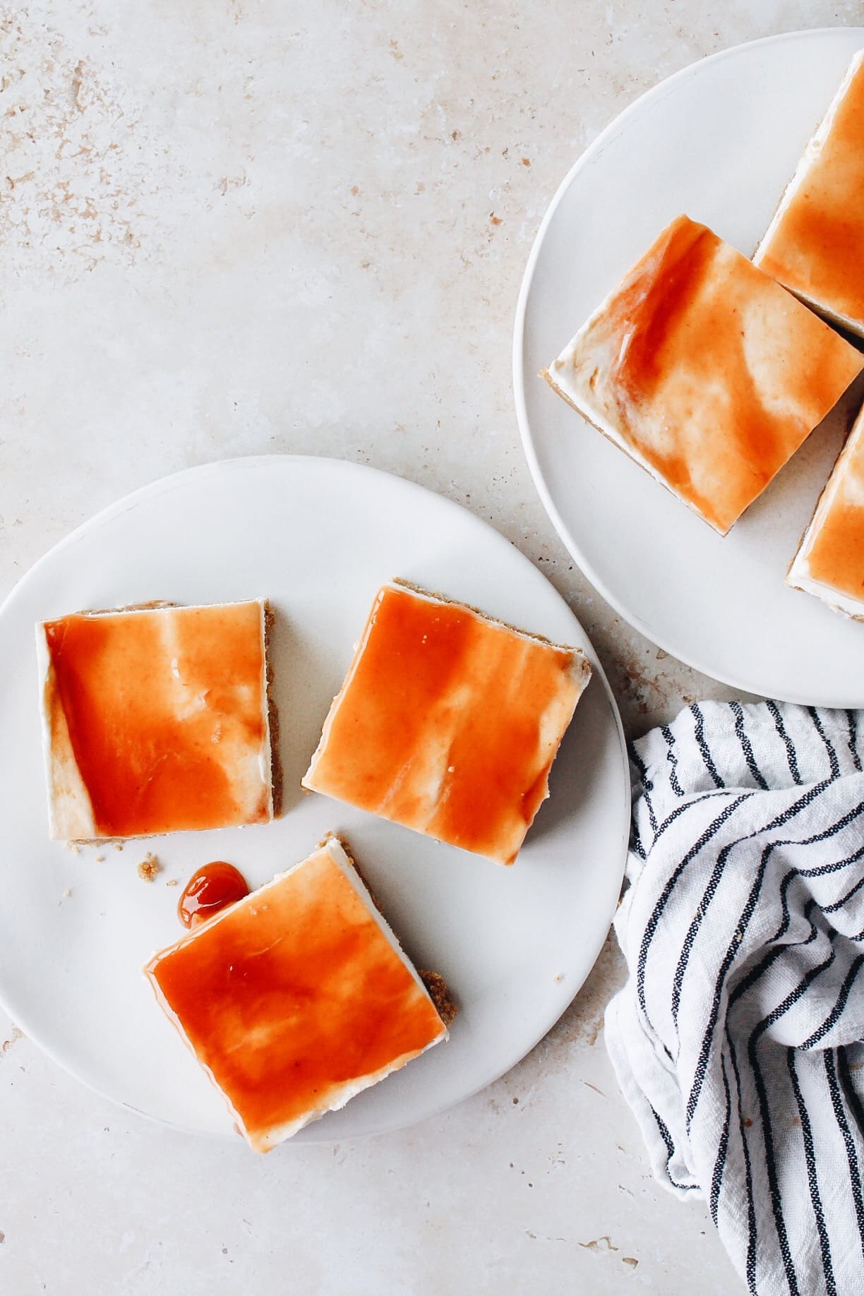 guava cheesecake bars on white plates with a striped napkin