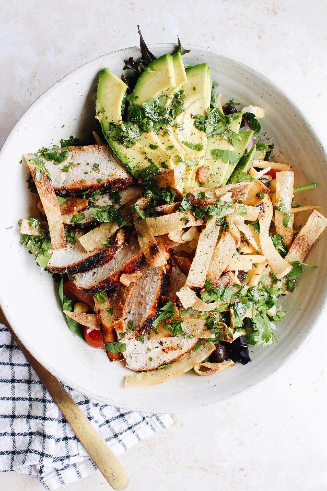 southwest chicken salad in a white bowl topped with avocado
