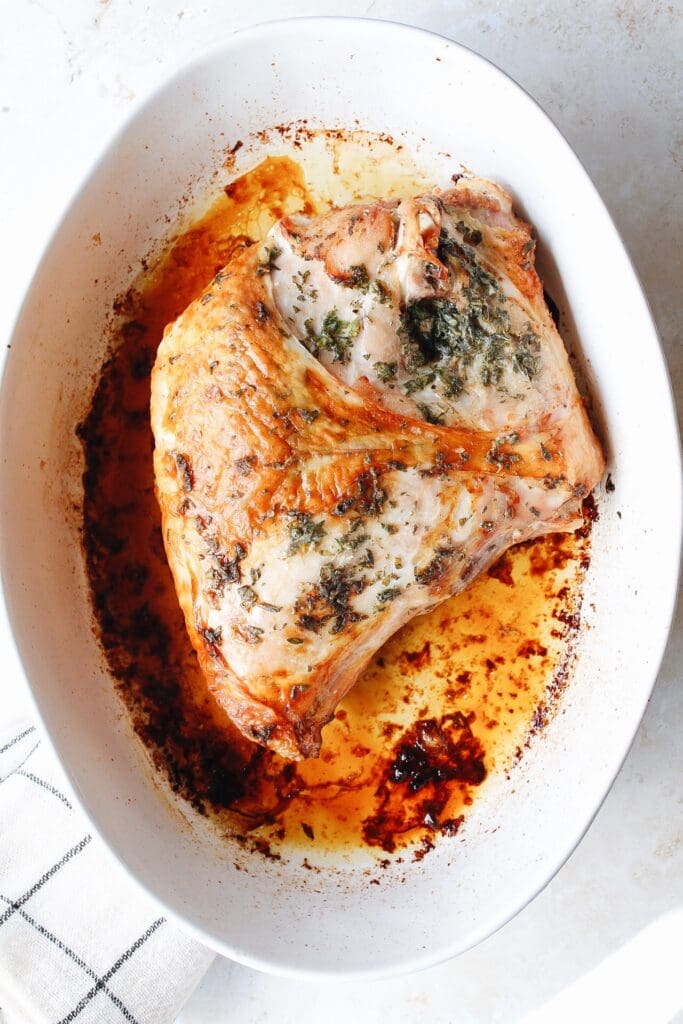 half turkey breast in a white baking dish
