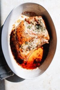 half turkey breast with herb breast in a white baking dish