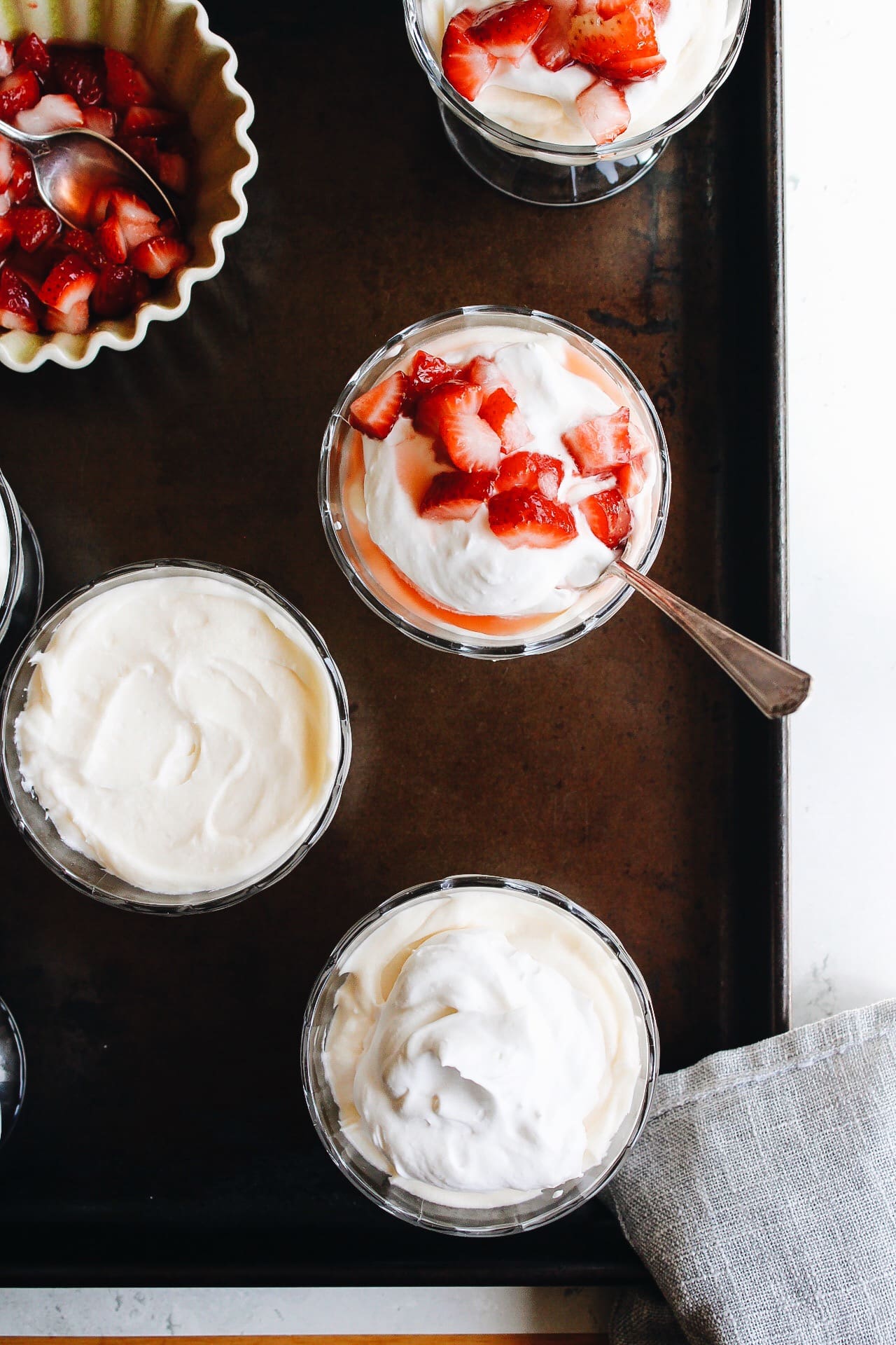 lemon mousse in serving cups topped with whipped cream and strawberries