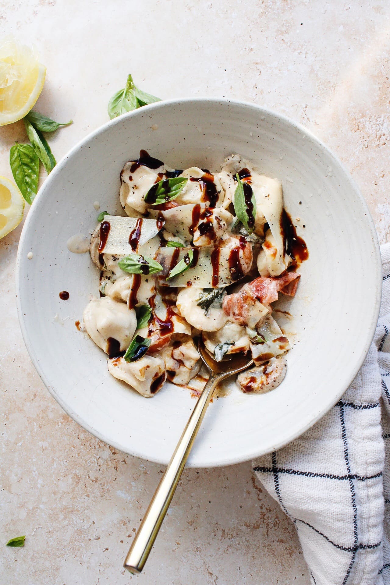 cheese tortellini with lemon cream sauce in a white bowl topped with balsamic glaze