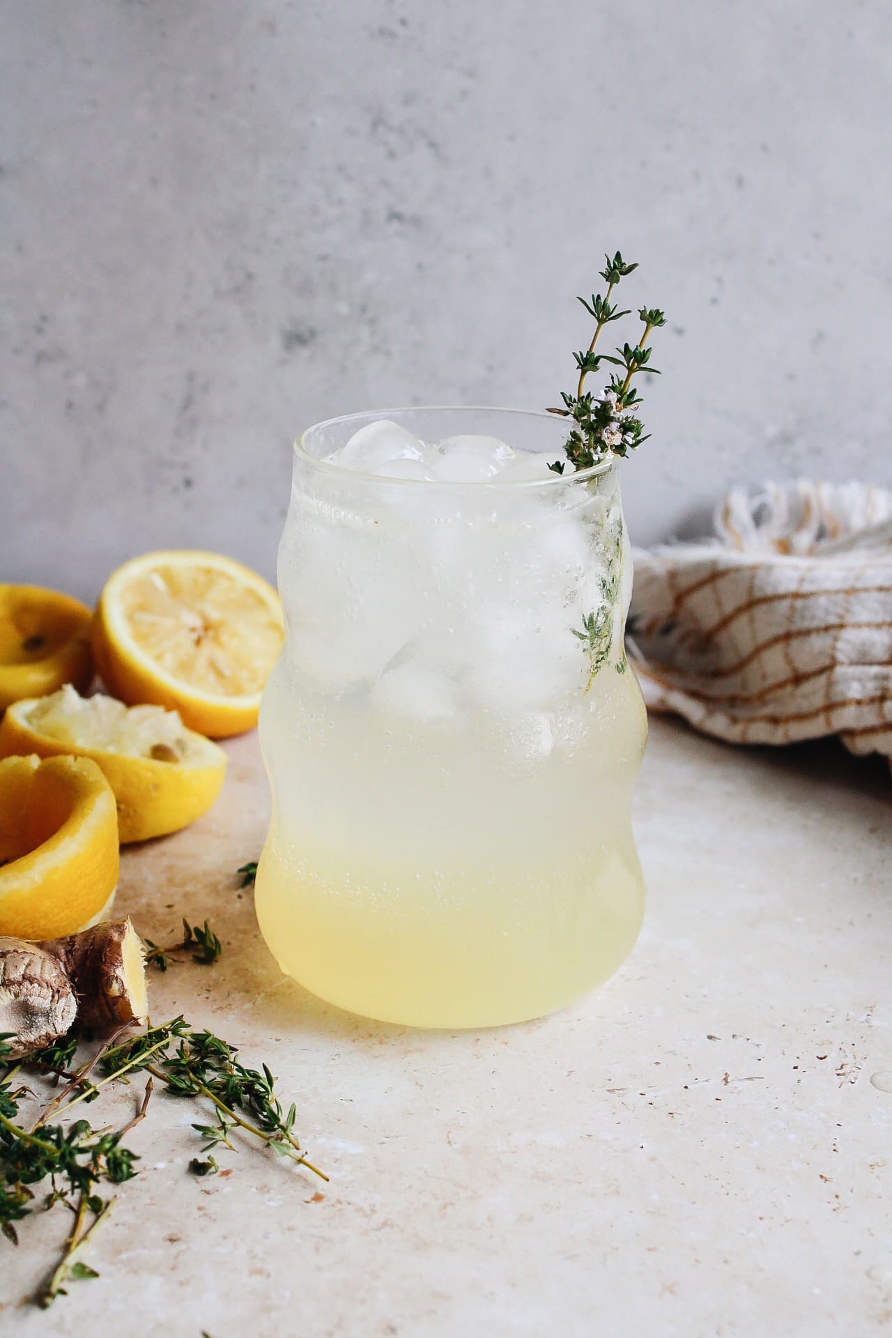 sparkling thyme lemonade in a clear glass with a thyme sprig